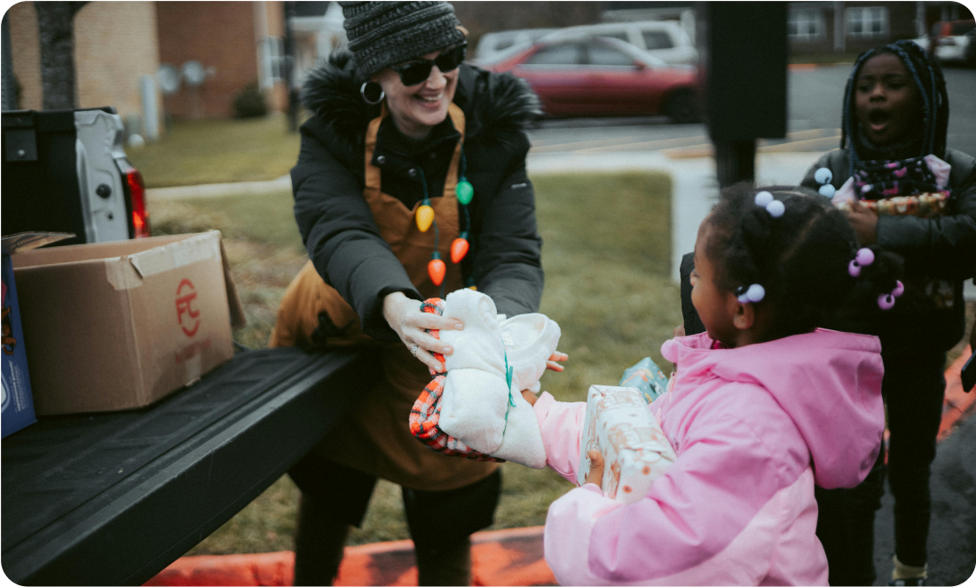 Volunteer distributing toys to children during a community event, with a focus on spreading joy and kindness through GoGo's RePlay Toys initiative.