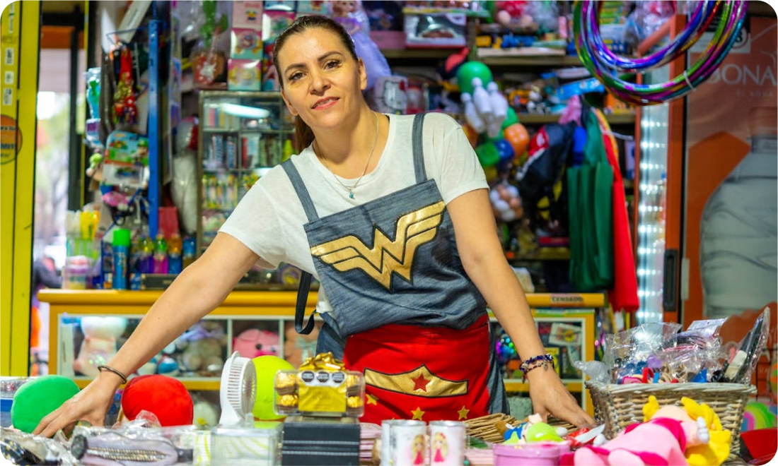 Woman wearing a Wonder Woman-themed outfit at a toy store, surrounded by colorful toys and merchandise, promoting community engagement and volunteer opportunities for GoGo's RePlay Toys.
